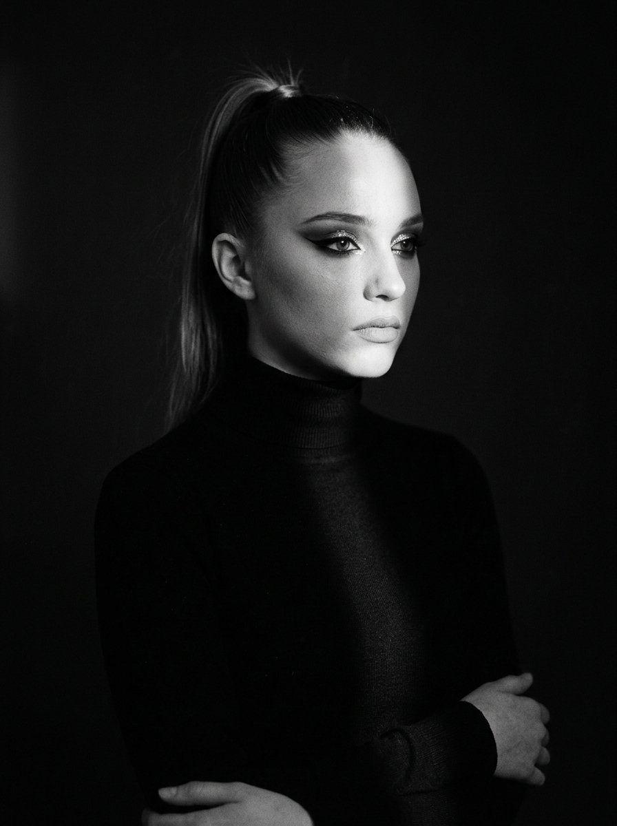 Prompt preview: Dramatic waist-up portrait of a pensive girl in the dim light of a studio. She's wearing a simple bl…